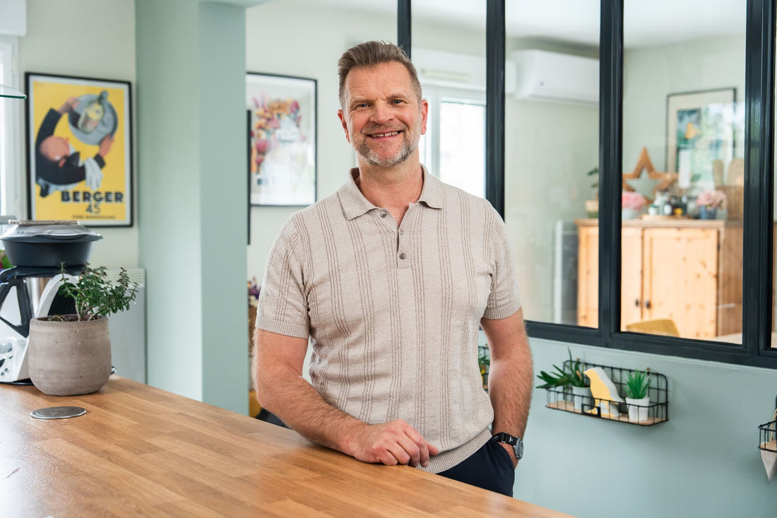 Homme de plus de 40 ans souriant et épanoui dans son intérieur, témoignant des résultats de la méthode Athlete40Plus sur sa vitalité et son bien-être au quotidien
