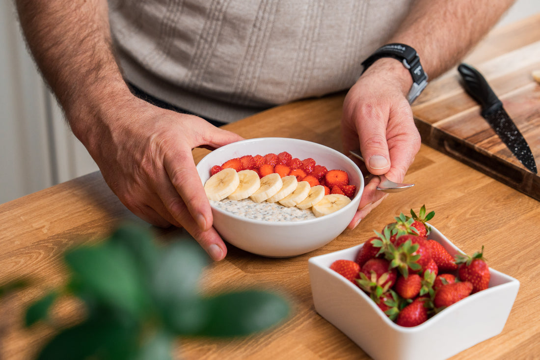 Homme préparant un bol de fruits frais et de céréales en cuisine, illustrant une nutrition de soutien métabolique adaptée à la santé durable et à la réduction de l'âge biologique après 40 ans.
