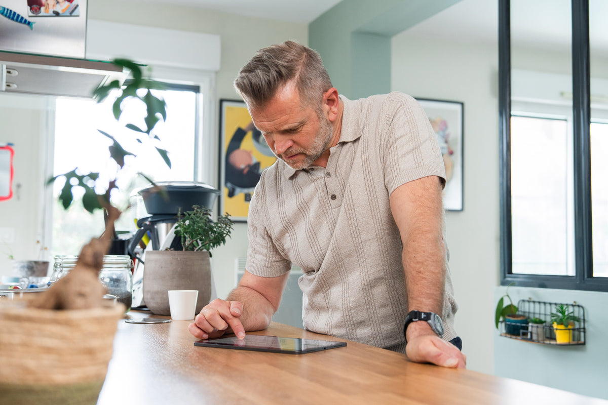 Homme actif de 50 ans consultant son programme de remise en forme, illustrant la reprise en main de sa santé biologique au quotidien.